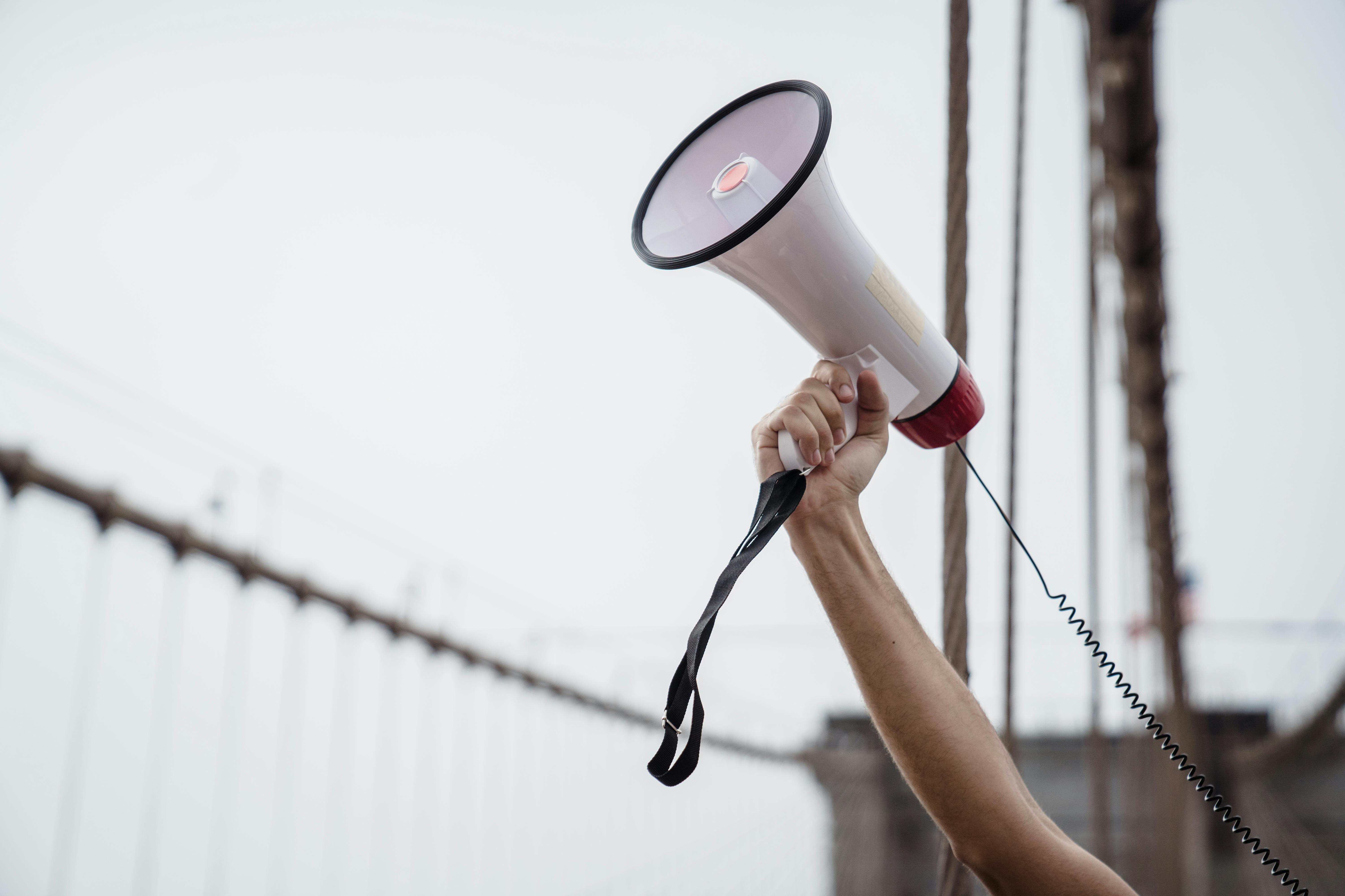 A hand holds up a megaphone making an announcement